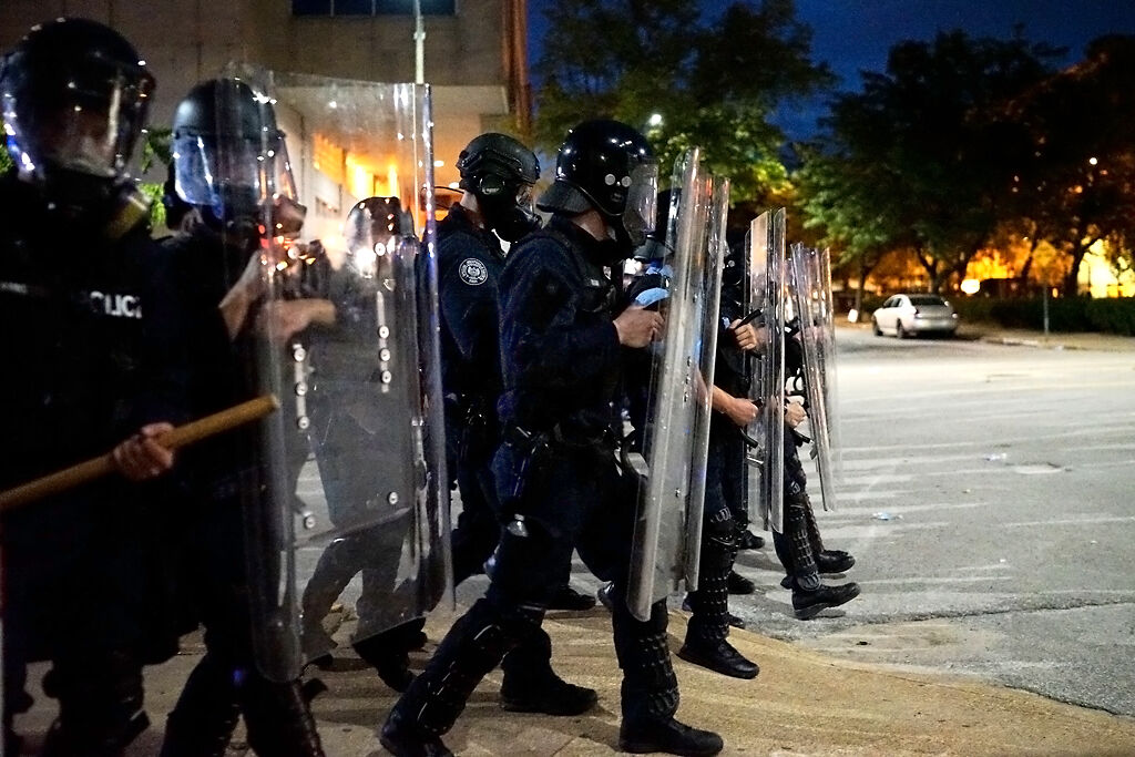 Riot police move forward after a group of protesters arrive at the St. Louis police headquarters Monday